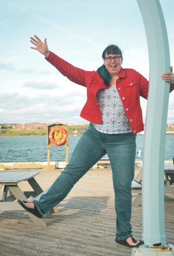 A photo of Amy holding on to a lamp post and waving